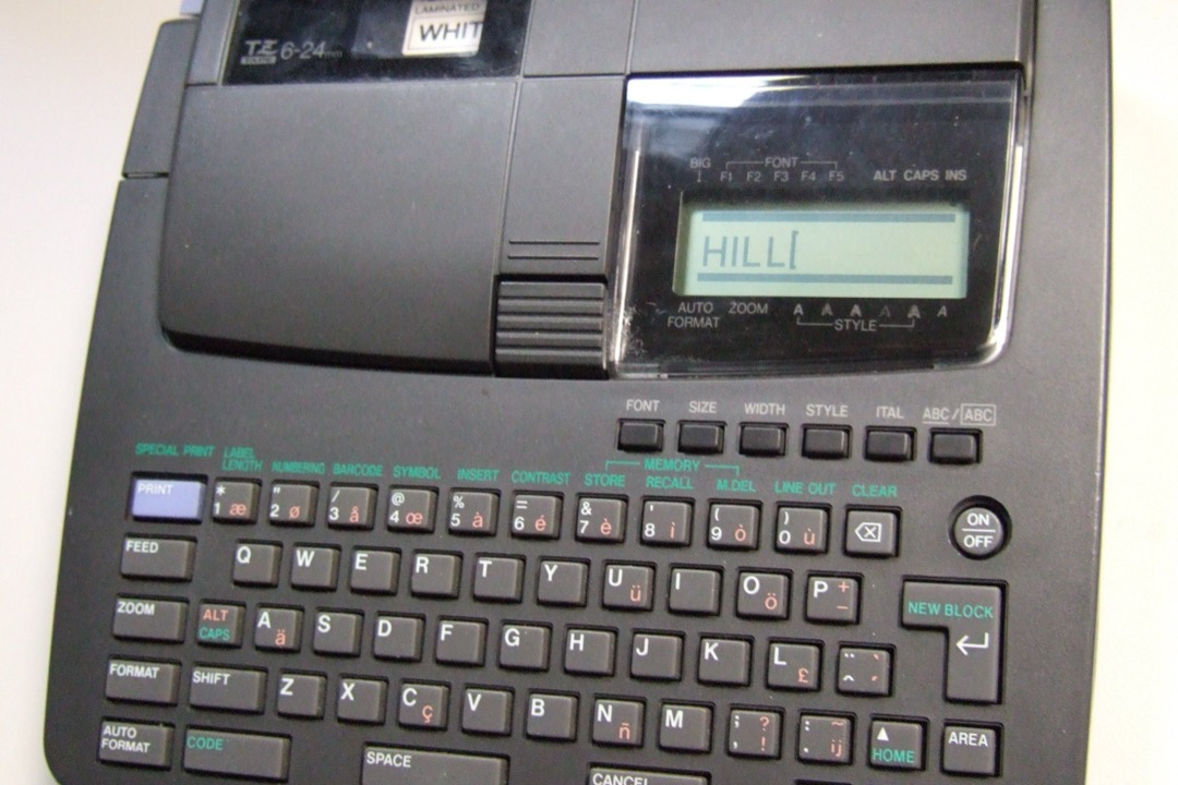 A handheld label maker printing a label on a desk
