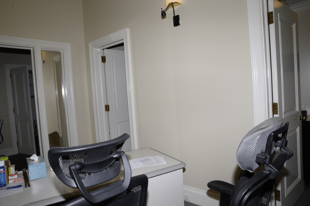 An adjustable ergonomic office chair positioned at a desk in a bright workspace